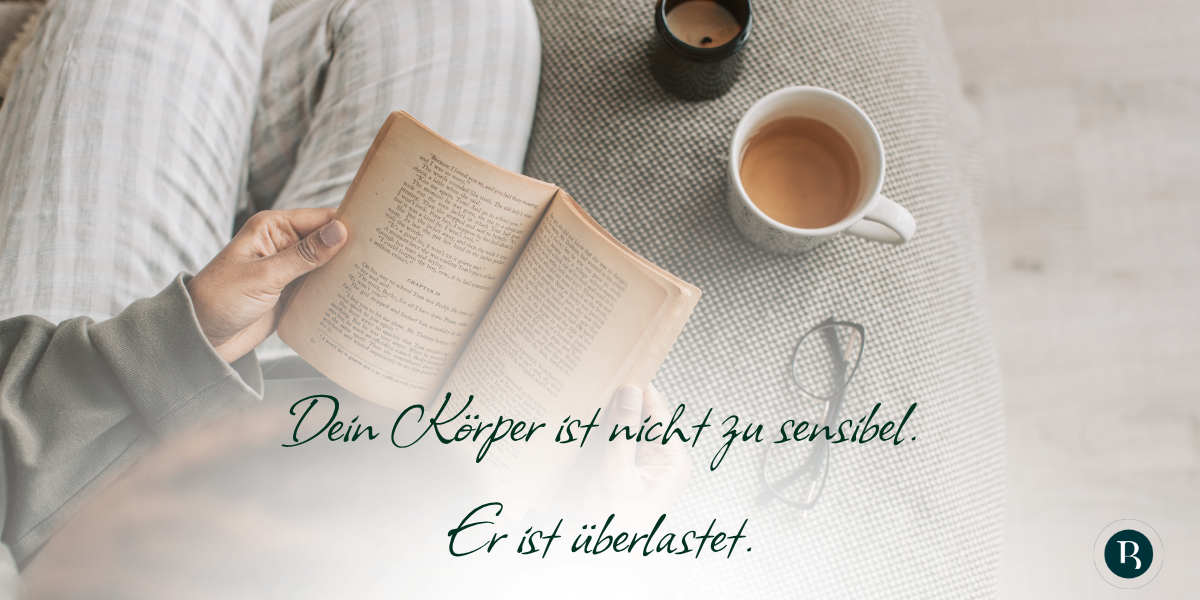Person hält Buch in der Hand (Perspektive von oben fotografiert), daneben stehen eine Kerze, eine Tasse Tee und eine Brille Text im Bild: Dein Körper ist nicht zu sensibel. Er ist überlastet.
